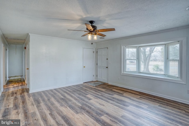 interior space with ceiling fan, hardwood / wood-style flooring, crown molding, and a textured ceiling