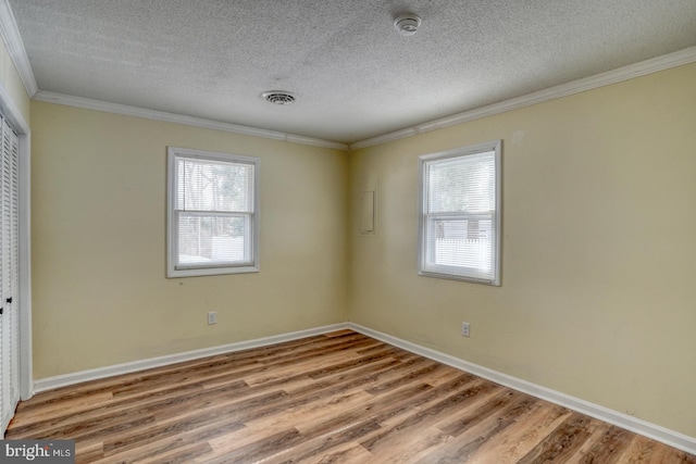 unfurnished bedroom with multiple windows, a closet, wood-type flooring, and crown molding