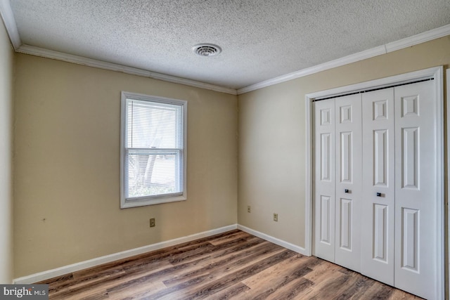 unfurnished bedroom featuring hardwood / wood-style flooring, crown molding, and a closet