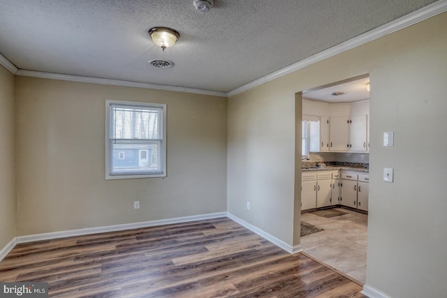 unfurnished dining area with light hardwood / wood-style flooring, crown molding, and a textured ceiling