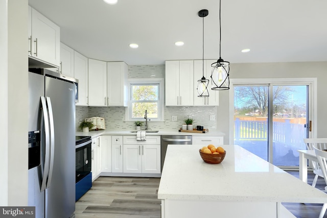 kitchen with decorative light fixtures, light stone countertops, sink, appliances with stainless steel finishes, and white cabinets