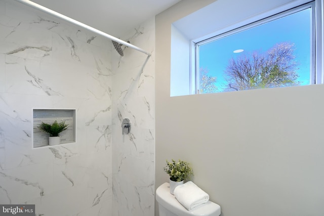 bathroom featuring tiled shower and toilet