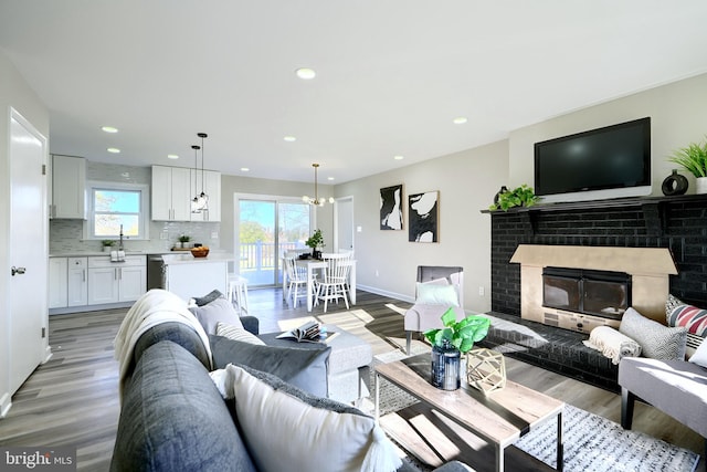 living room with light hardwood / wood-style flooring, sink, and a brick fireplace