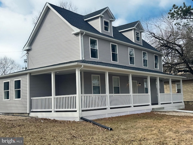 view of front facade with covered porch, roof with shingles, and a front lawn