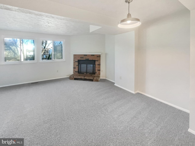 unfurnished living room featuring a brick fireplace, carpet flooring, and a textured ceiling