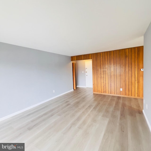 spare room featuring light wood-type flooring and wooden walls