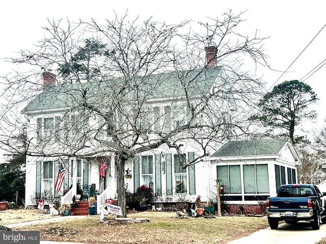 view of front of house featuring entry steps, a front lawn, and a chimney