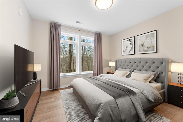 bedroom with baseboards, visible vents, and light wood finished floors