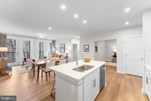 kitchen with a sink, white cabinetry, open floor plan, dishwasher, and an island with sink