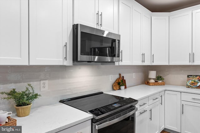 kitchen featuring light stone counters, electric range, white cabinetry, backsplash, and stainless steel microwave