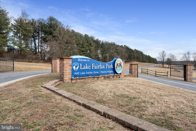 community / neighborhood sign featuring a lawn and fence