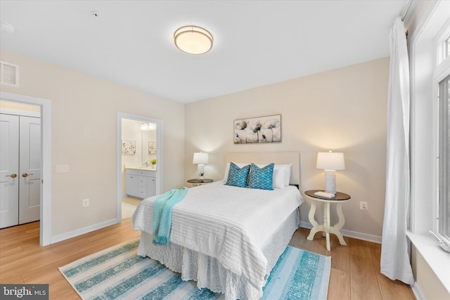 bedroom featuring light wood-style floors, baseboards, and connected bathroom