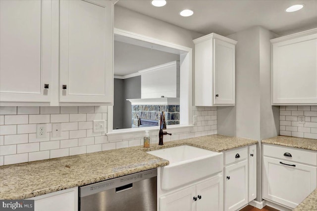 kitchen with a sink, light stone countertops, white cabinetry, and stainless steel dishwasher