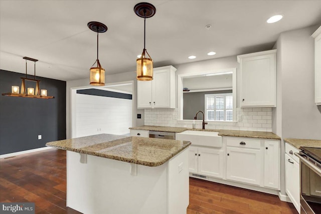 kitchen with a sink, white cabinetry, a kitchen breakfast bar, dark wood-style floors, and pendant lighting