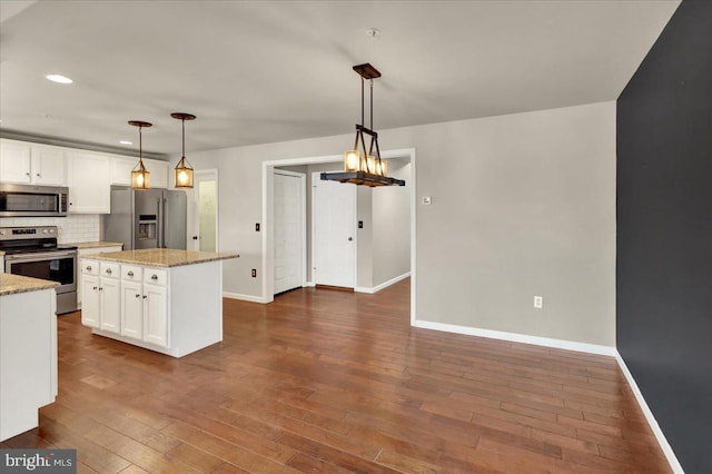 kitchen featuring hanging light fixtures, appliances with stainless steel finishes, and white cabinetry