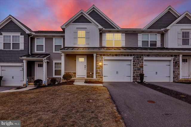 multi unit property featuring a garage, stone siding, driveway, and a standing seam roof