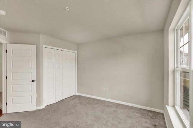 unfurnished bedroom with baseboards, a closet, visible vents, and light colored carpet