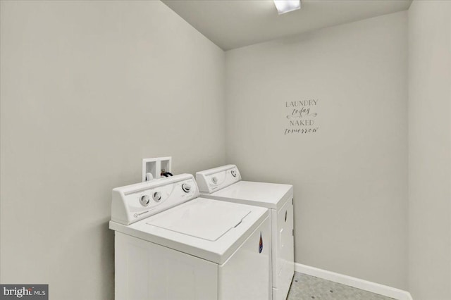 washroom featuring laundry area, baseboards, and separate washer and dryer