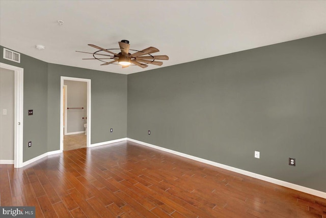 empty room featuring dark wood-style floors, visible vents, ceiling fan, and baseboards