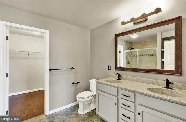 bathroom with double vanity, a stall shower, a spacious closet, and a sink