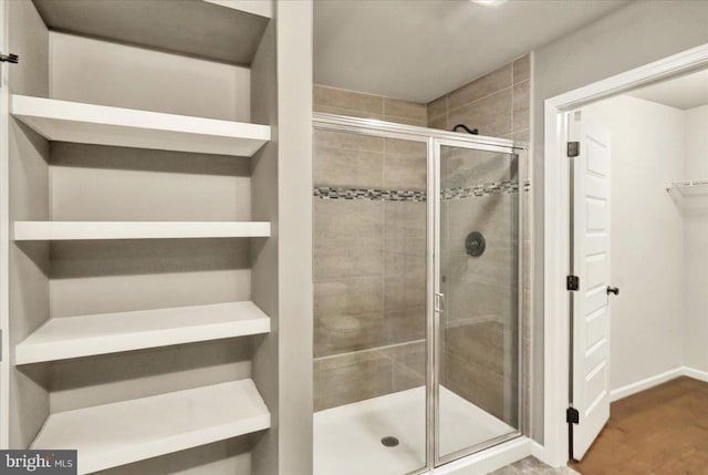 bathroom with a shower stall, baseboards, and wood finished floors