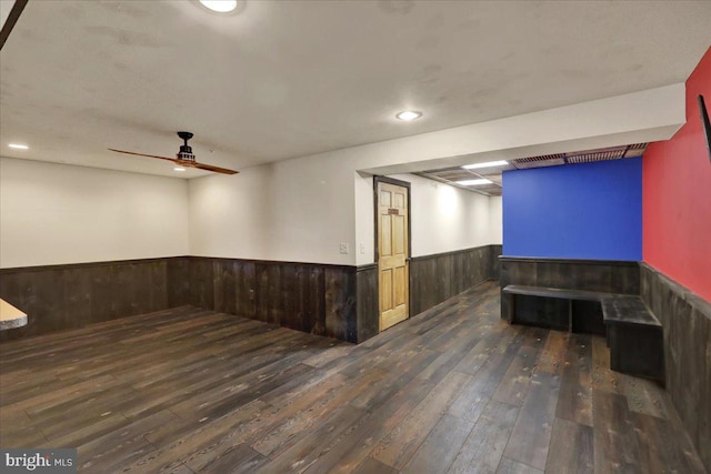 interior space featuring wooden walls, a ceiling fan, wainscoting, dark wood-style flooring, and recessed lighting