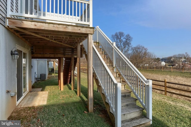 exterior space featuring central air condition unit, fence, and a lawn