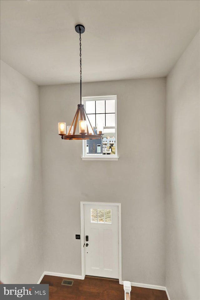 foyer with a notable chandelier, baseboards, visible vents, and dark wood-type flooring