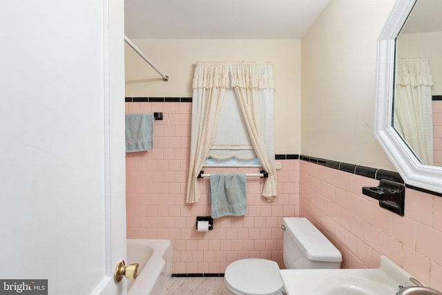 6510 Oakwood Dr, Falls Church, VA 22041 - bathroom with a tub, tile walls, toilet, and wainscoting