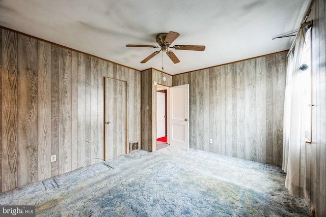 spare room with ornamental molding, carpet floors, and wood walls