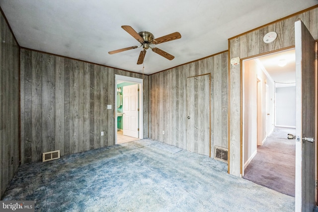 spare room with ceiling fan, ornamental molding, light colored carpet, and wooden walls