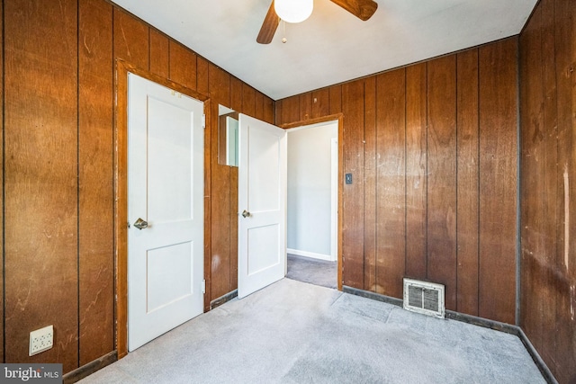 carpeted spare room featuring ceiling fan and wood walls