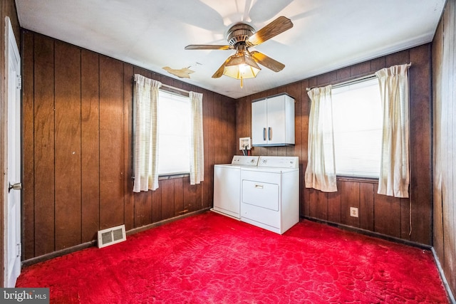 laundry room with cabinets, washer and dryer, wooden walls, and a healthy amount of sunlight