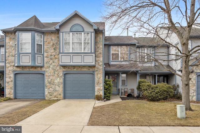 view of property with a garage, stone siding, driveway, and a shingled roof