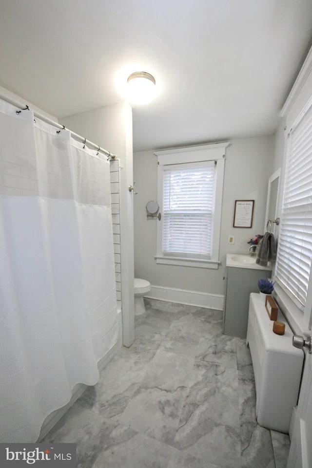 bathroom featuring toilet, vanity, baseboards, marble finish floor, and shower / bath combo with shower curtain