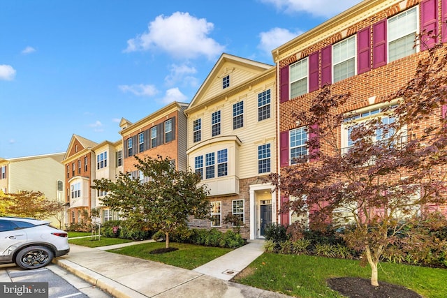 townhome / multi-family property with stone siding, a residential view, and a front yard