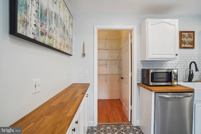 kitchen with wood counters, white cabinetry, stainless steel appliances, and decorative backsplash