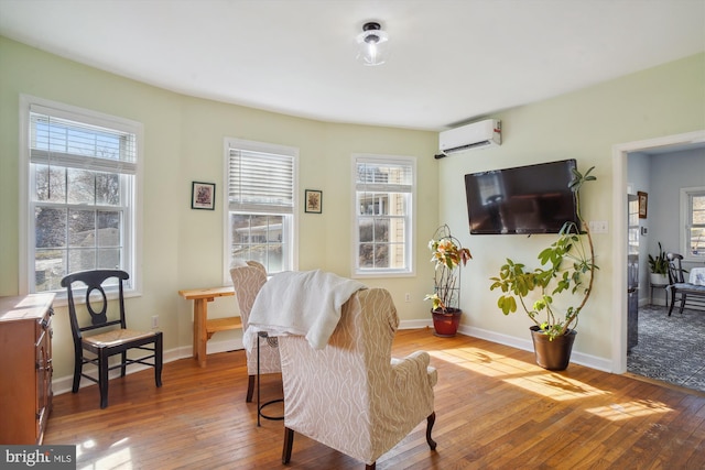 living area with a wall mounted AC and hardwood / wood-style flooring