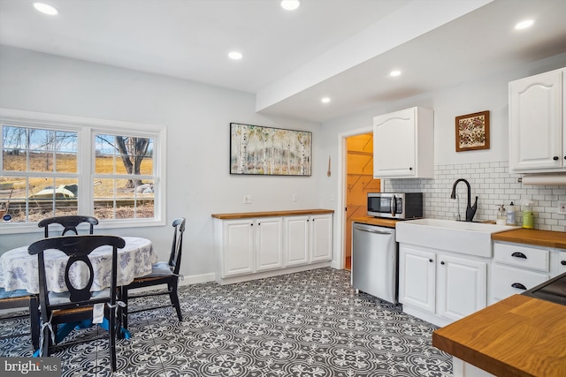 kitchen featuring white cabinets, decorative backsplash, stainless steel appliances, and sink