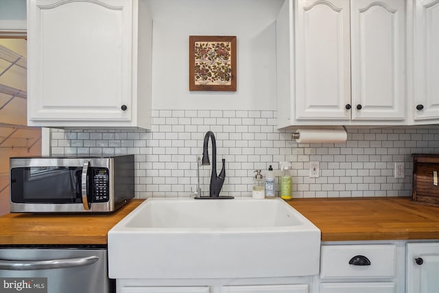 kitchen featuring stainless steel appliances, sink, white cabinets, decorative backsplash, and wooden counters