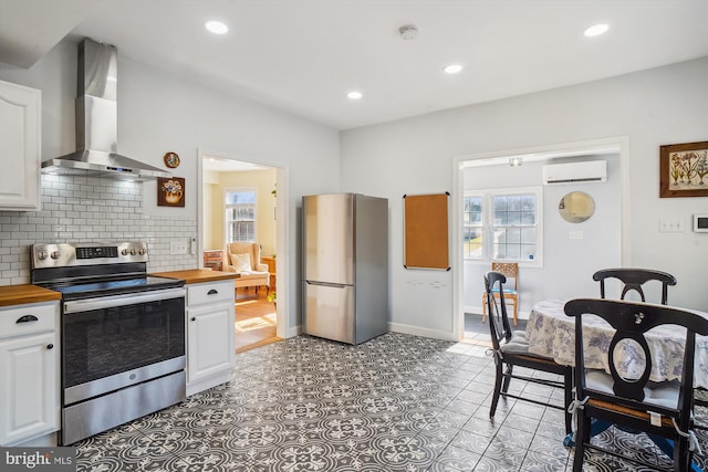 kitchen featuring white cabinets, wood counters, stainless steel appliances, and wall chimney range hood