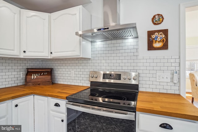 kitchen with stainless steel electric range, tasteful backsplash, butcher block counters, extractor fan, and white cabinetry