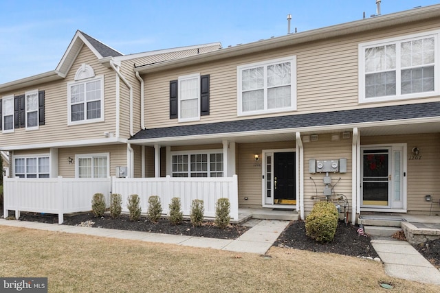 view of property featuring a front yard, a shingled roof, and entry steps