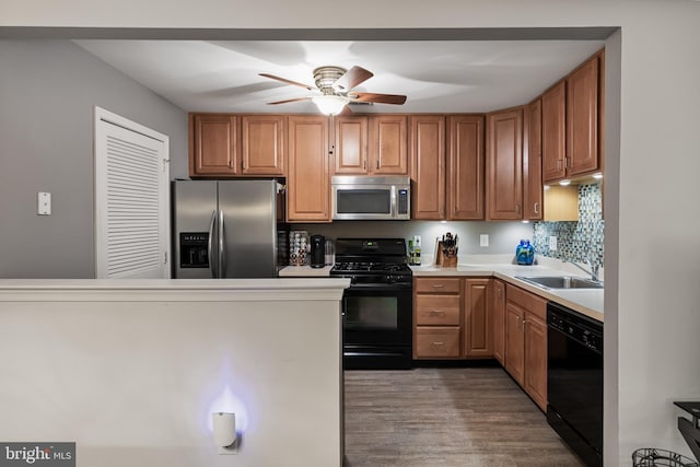 kitchen with light countertops, a sink, black appliances, wood finished floors, and a ceiling fan