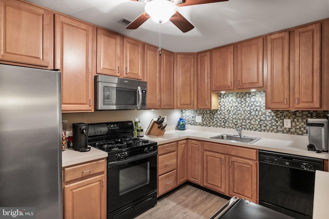 kitchen featuring light countertops, black appliances, tasteful backsplash, visible vents, and a sink