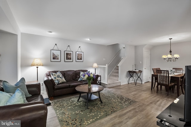 living area featuring wood finished floors, baseboards, an inviting chandelier, and stairs