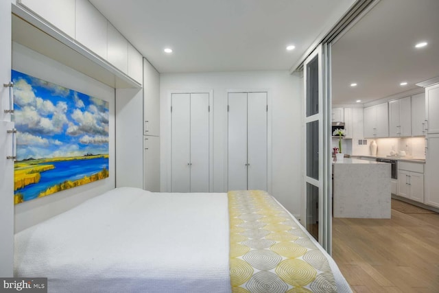 bedroom featuring light wood-style flooring, multiple closets, and recessed lighting