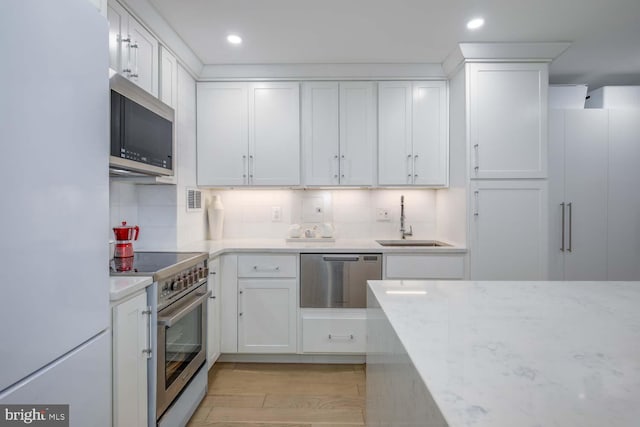 kitchen featuring appliances with stainless steel finishes, decorative backsplash, a sink, and white cabinets