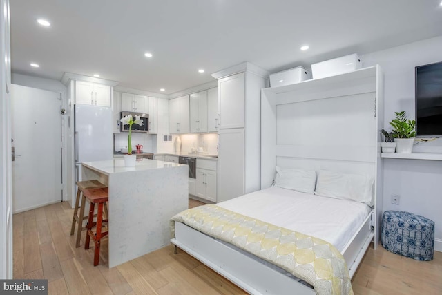 bedroom featuring light wood-type flooring, recessed lighting, and freestanding refrigerator