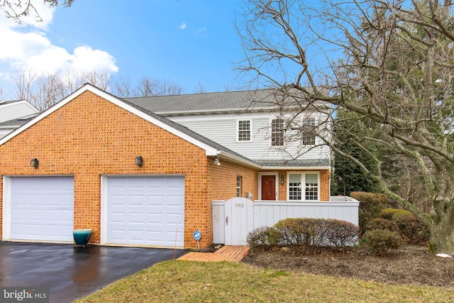 traditional-style house featuring driveway, brick siding, roof with shingles, and an attached garage